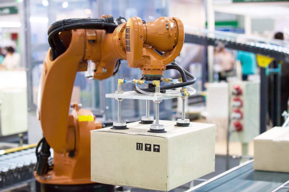 Automated production line robotic arm lifting a box