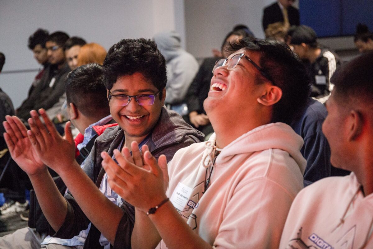 Two young manufacturing professionals laughing and clapping