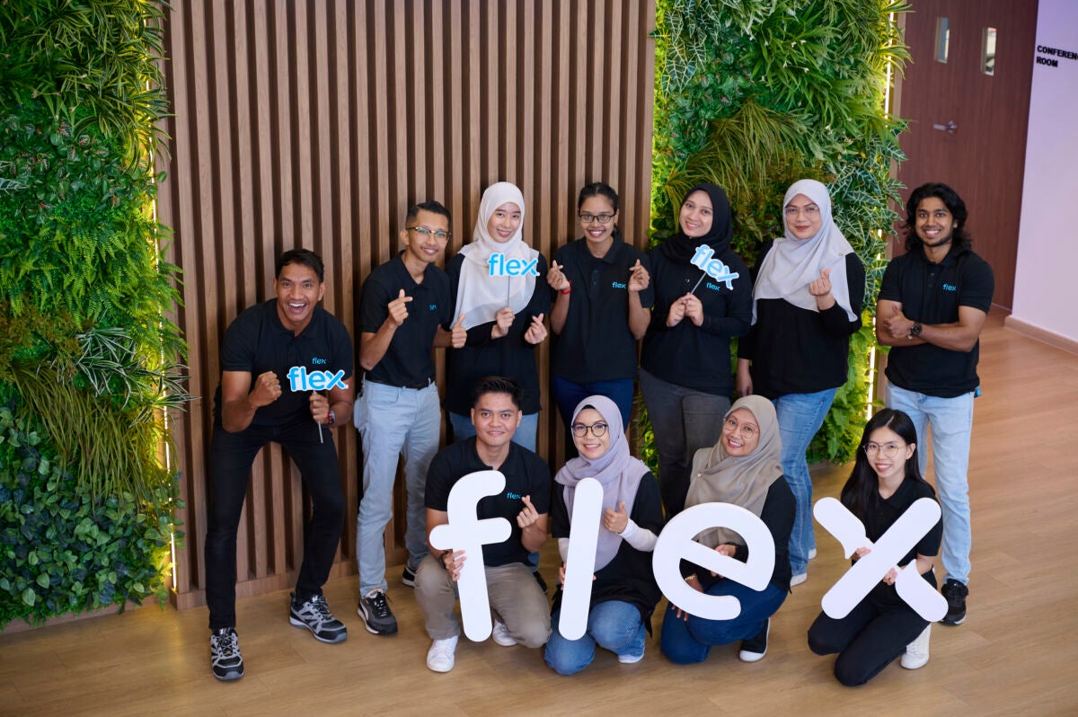 Eine Gruppe von Flex-Mitarbeitern in Penang steht und kniet und hält Flex-Schilder
