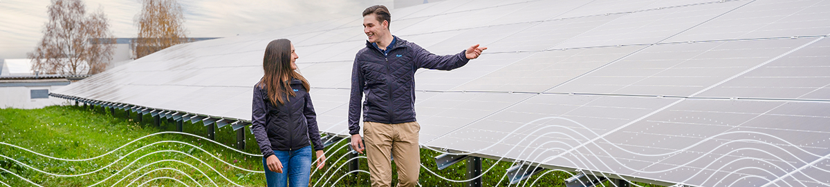 Dos empleados flexibles caminando frente a paneles solares en un césped verde