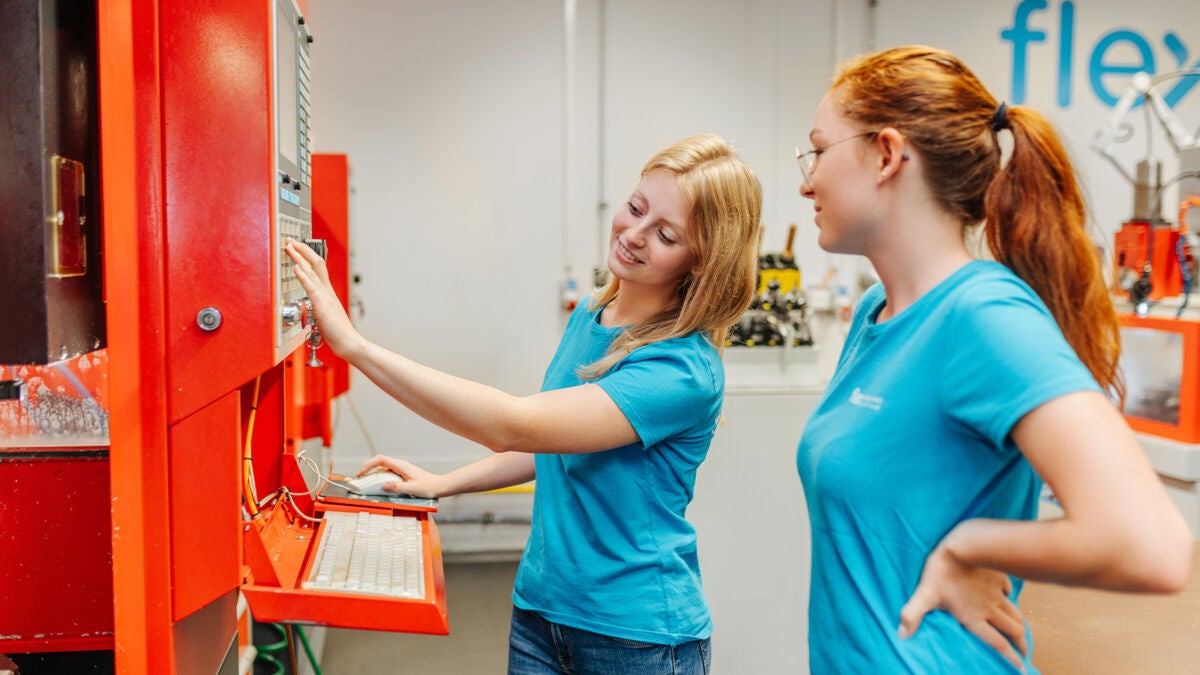 Two female apprentices working together on a machine
