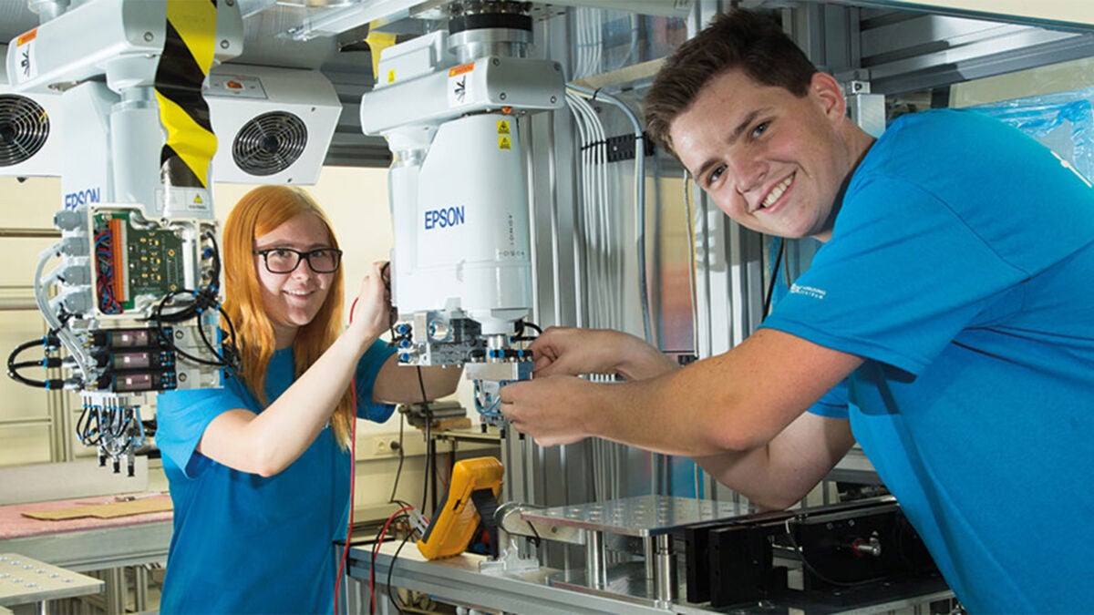 Two apprentices working on a machine