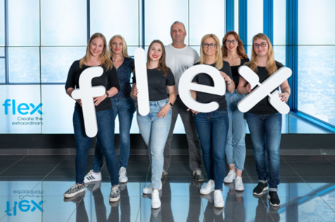 Flex-Mitarbeiter in Ungarn halten einzelne Buchstaben, aus denen das Flex-Logo besteht