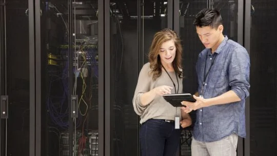 Two people collaborating on a tablet in a data center