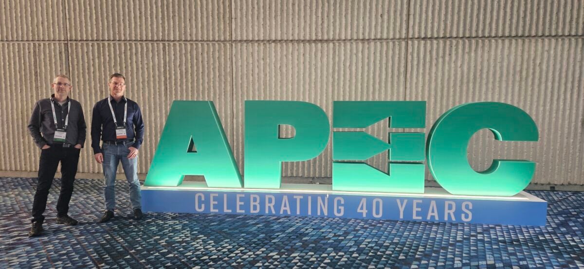 Flex Power Modules team members standing next to APEC sign at APEC 2025