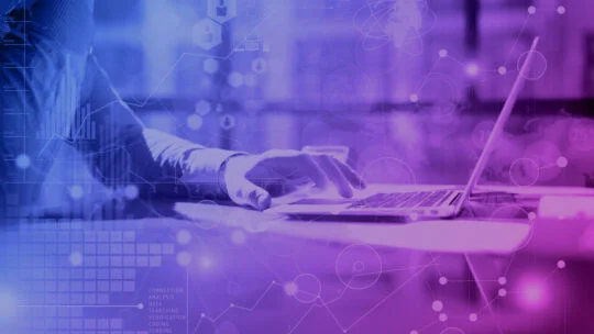 Person working on a laptop with a purple and blue digital overlay featuring abstract technology icons, data charts, and network symbols.