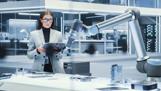 Mujer controlando un brazo robótico de fabricación en un laboratorio sanitario