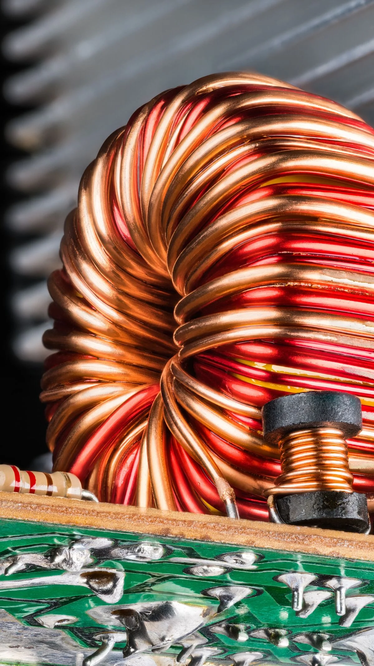 Ferrite core inductors wrapped with copper wire. Electronic toroid and solenoid coils. Passive electrical components soldered on bottom side of circuit board detail.