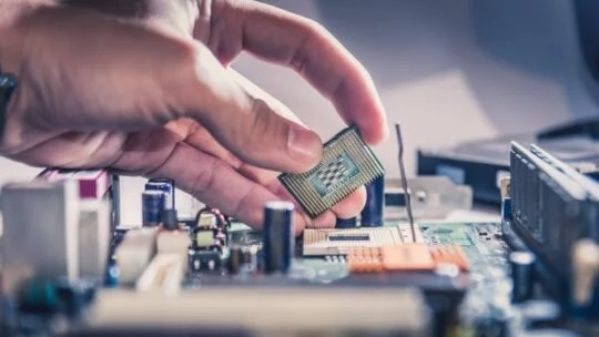 Technician putting the CPU on the socket of the computer motherboard