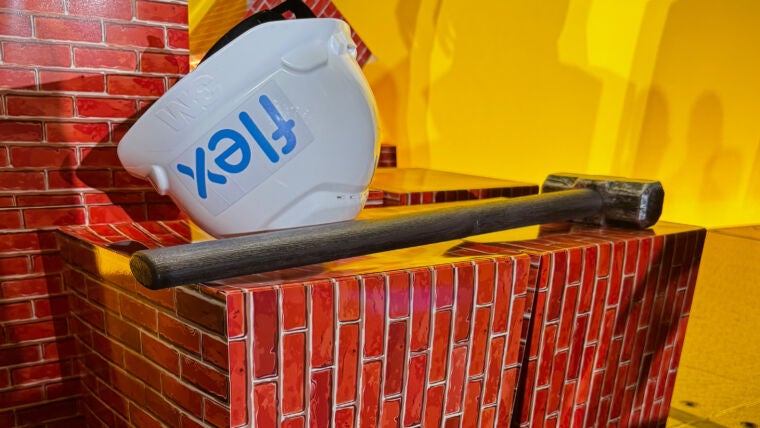 砖墙上放着一把锤子和一顶Flex安全帽