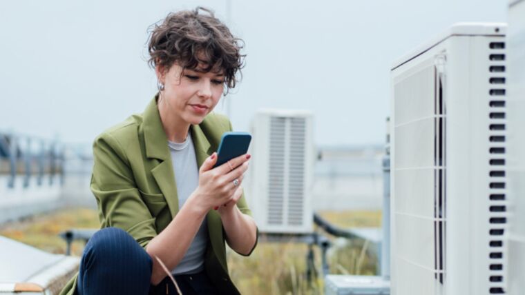 Woman getting readings on her phone for an HVAC system