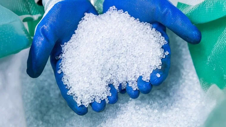 Persona con guantes de goma manipulando materiales plásticos reciclados