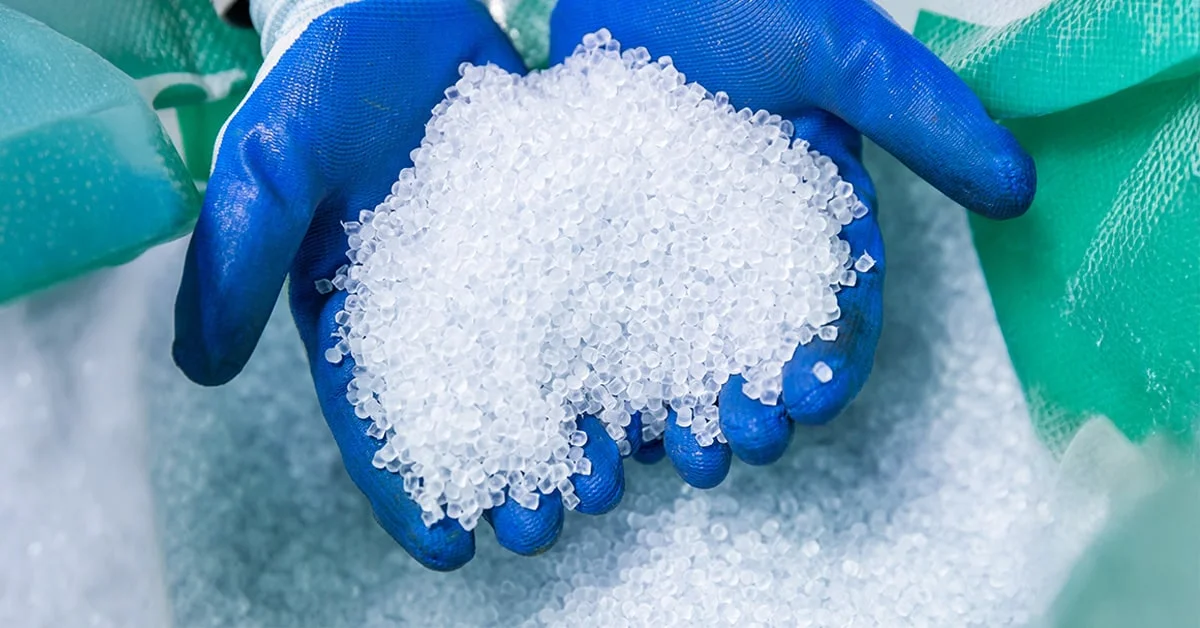 Person wearing rubber gloves handling recycled plastic materials