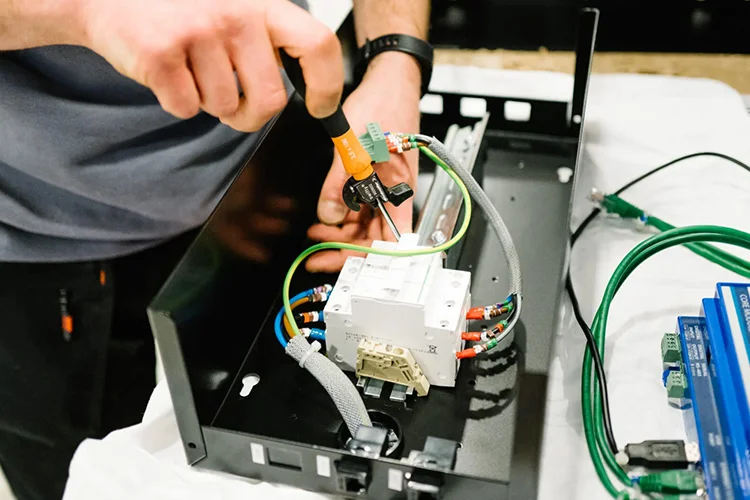 技术人员正在组装电源模块，将电线和组件连接到金属外壳内。.