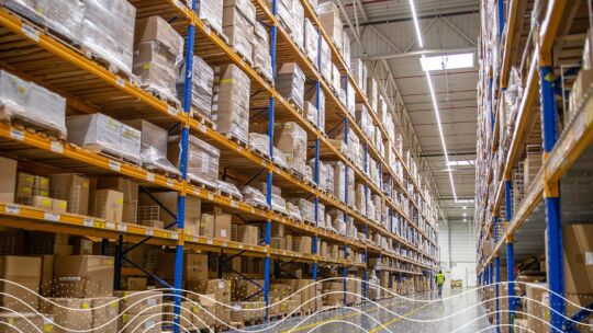 Flur eines Lagerhauses mit Kisten, die sich vom Boden bis zur Decke in Regalen stapeln.