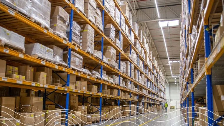 Hallway of a warehouse with boxes stacked on shelves from floor to ceiling