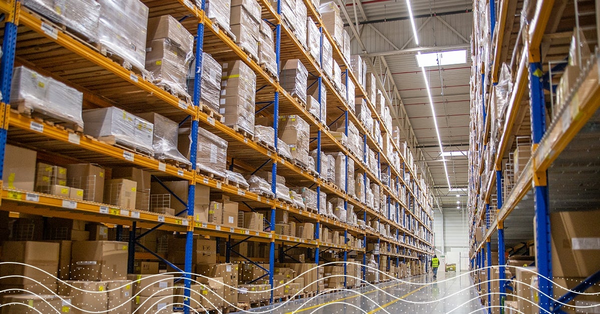 Hallway of a warehouse with boxes stacked on shelves from floor to ceiling