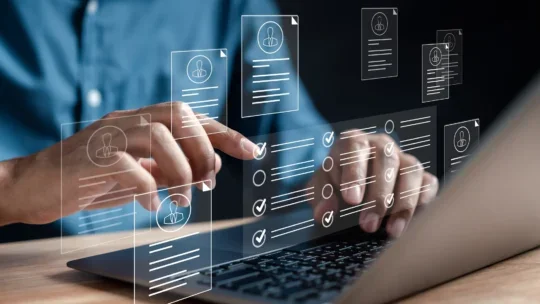 Hands typing on a laptop keyboard with transparent digital resume and checklist icons floating above the screen