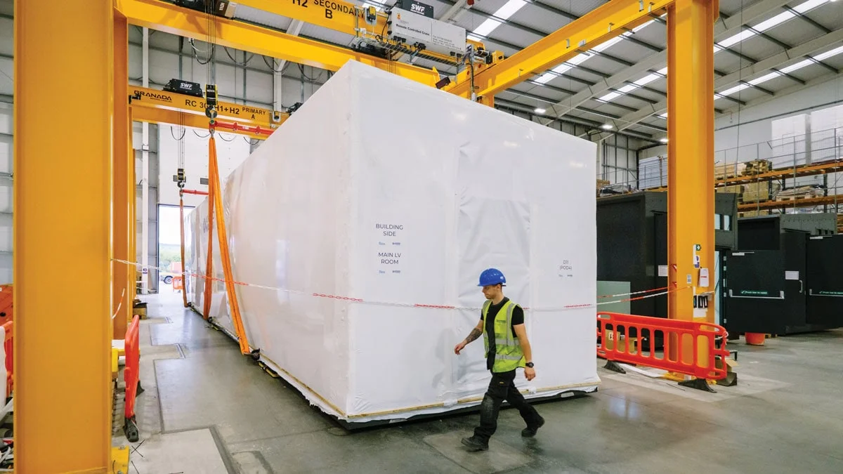 Person walking in front of a prefabricated modular data center enclosure ready for deployment