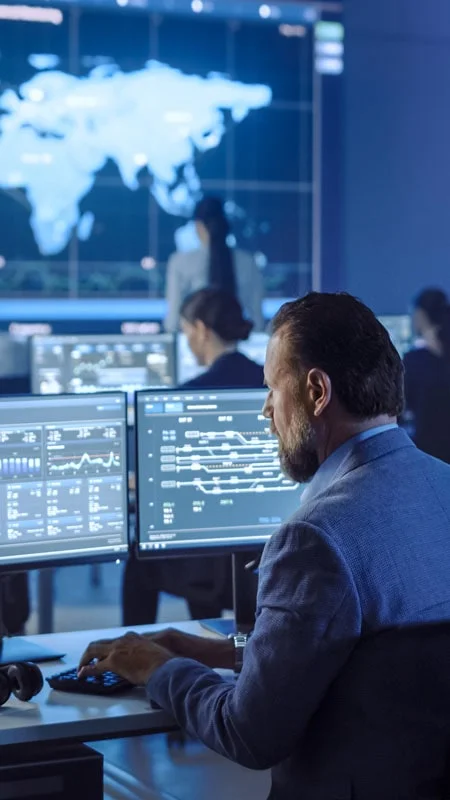 Professional at a computer with desktop showing graphs and charts