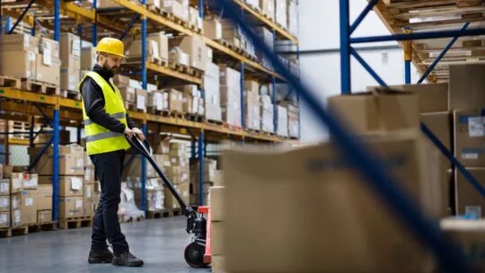 Male warehouse worker pulling a pallet of materials