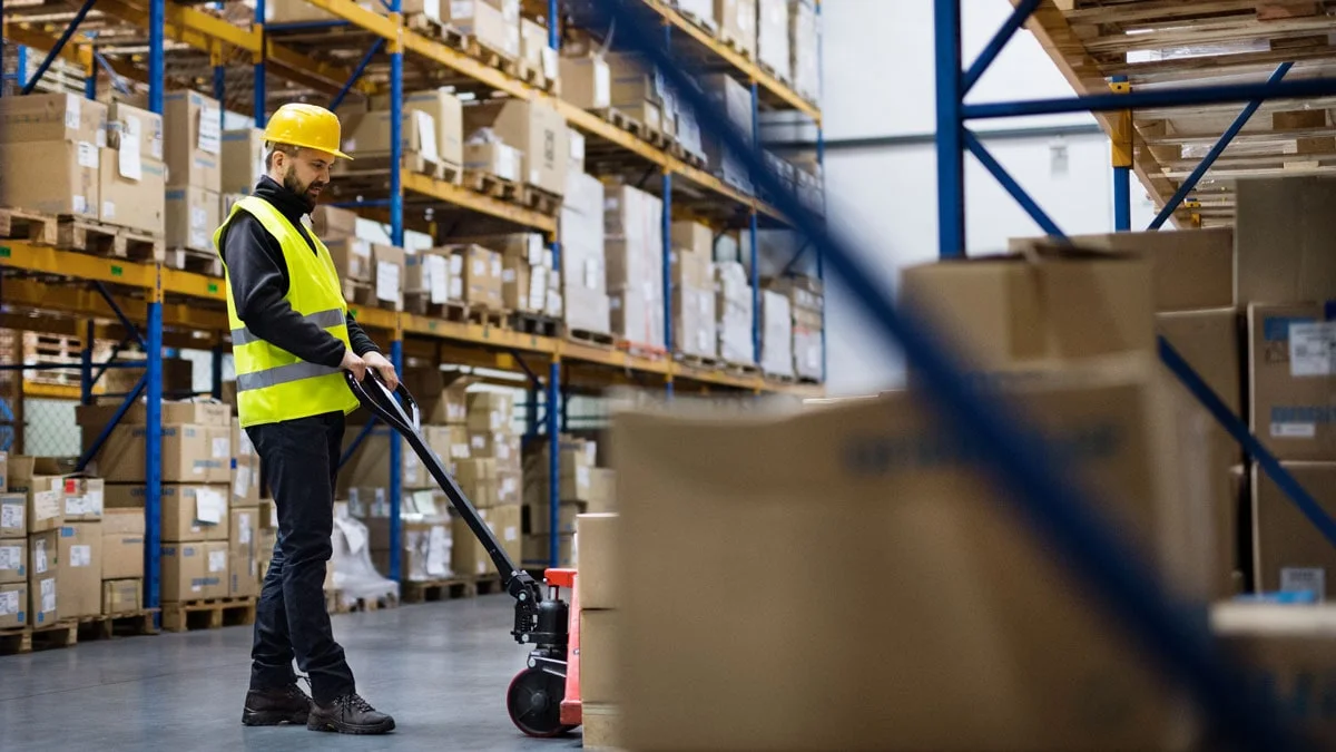Male warehouse worker pulling a pallet of materials