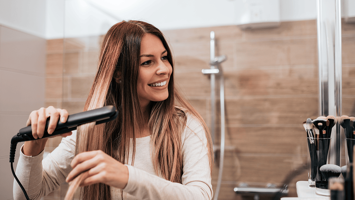 Woman using a personal care lifestyle product: hair straightener